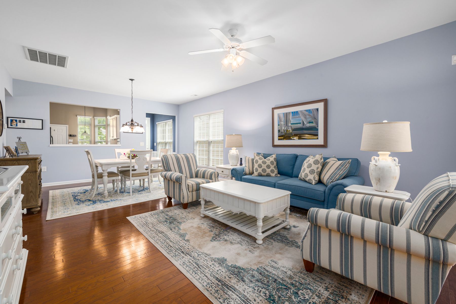 Bright living room with clean blue upholstery and area rugs